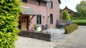 A brick house with a sloped roof, a front porch with a bench, and a gravel driveway. - Holiday Home in South Limburg With a Terrace (Klimmen)