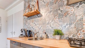 Une cuisine dotée d’un plan de travail en bois, d’un évier en acier inoxydable et d’un dosseret carrelé.