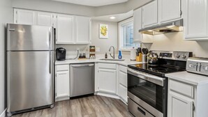 A modern kitchen with white cabinets, stainless steel appliances, and a built-in oven. - Home Sweet Getaway - Perfect for Girl's Trips & Families (Wisconsin Dells)