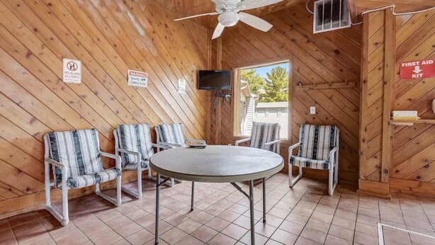 A wooden interior with a round table and four striped chairs, a ceiling fan, and a 'First Aid Kit' sign. - Home Sweet Getaway - Perfect for Girl's Trips & Families (Wisconsin Dells)
