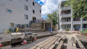 A patio area with outdoor seating, a barbecue grill, and a stone wall. - Home Sweet Getaway - Perfect for Girl's Trips & Families (Wisconsin Dells)