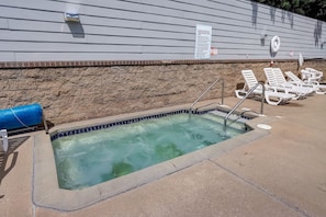 A small outdoor swimming pool with a stone wall and a blue cover.