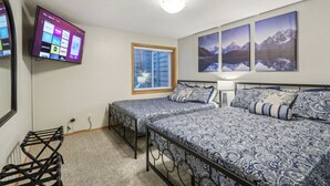A bedroom with two beds, a TV on the wall, and mountain landscape paintings. - Home Sweet Getaway - Perfect for Girl's Trips & Families (Wisconsin Dells)