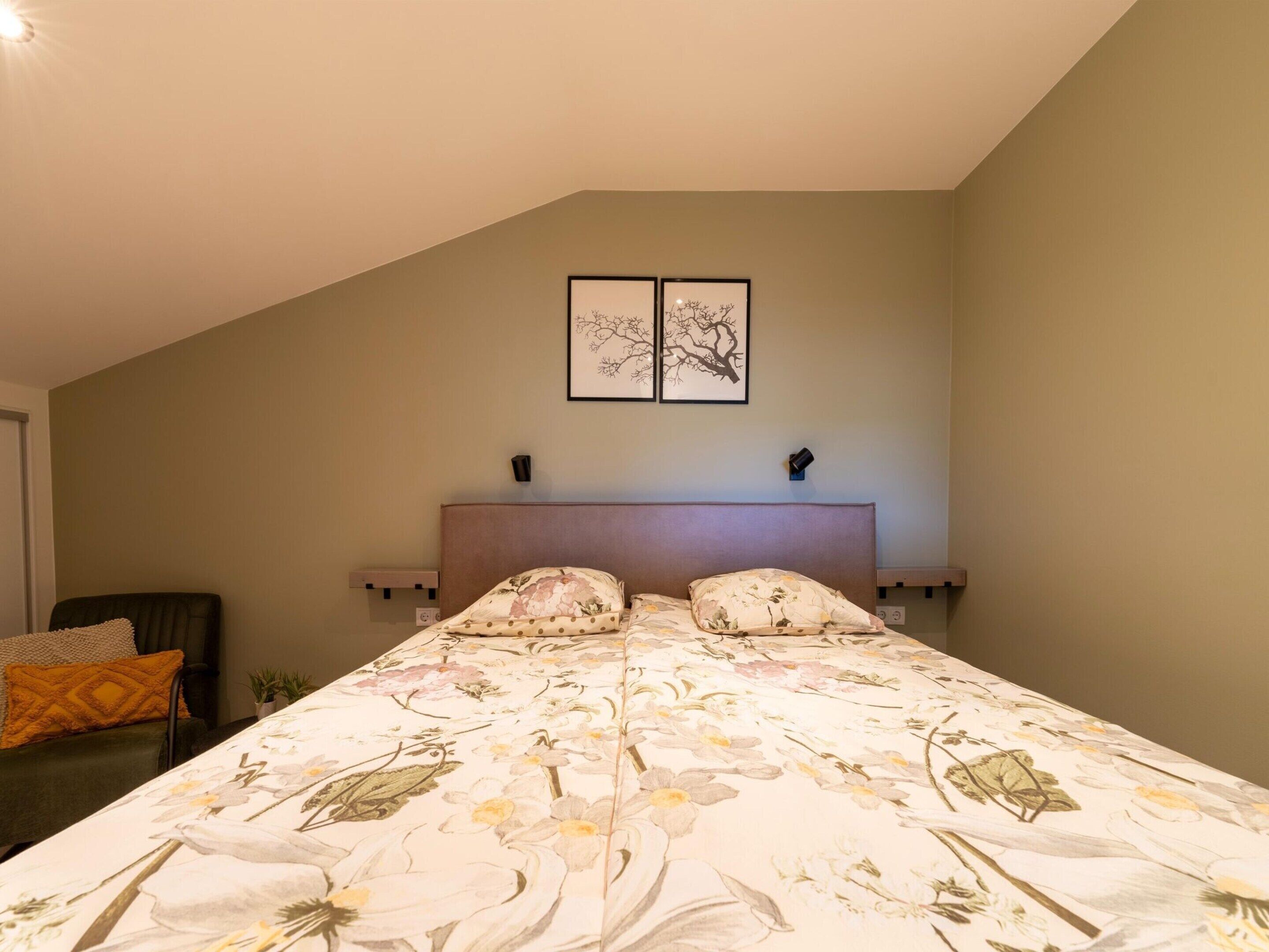 Une chambre à coucher avec un lit, deux lampes fixées au mur et deux tableaux encadrés.