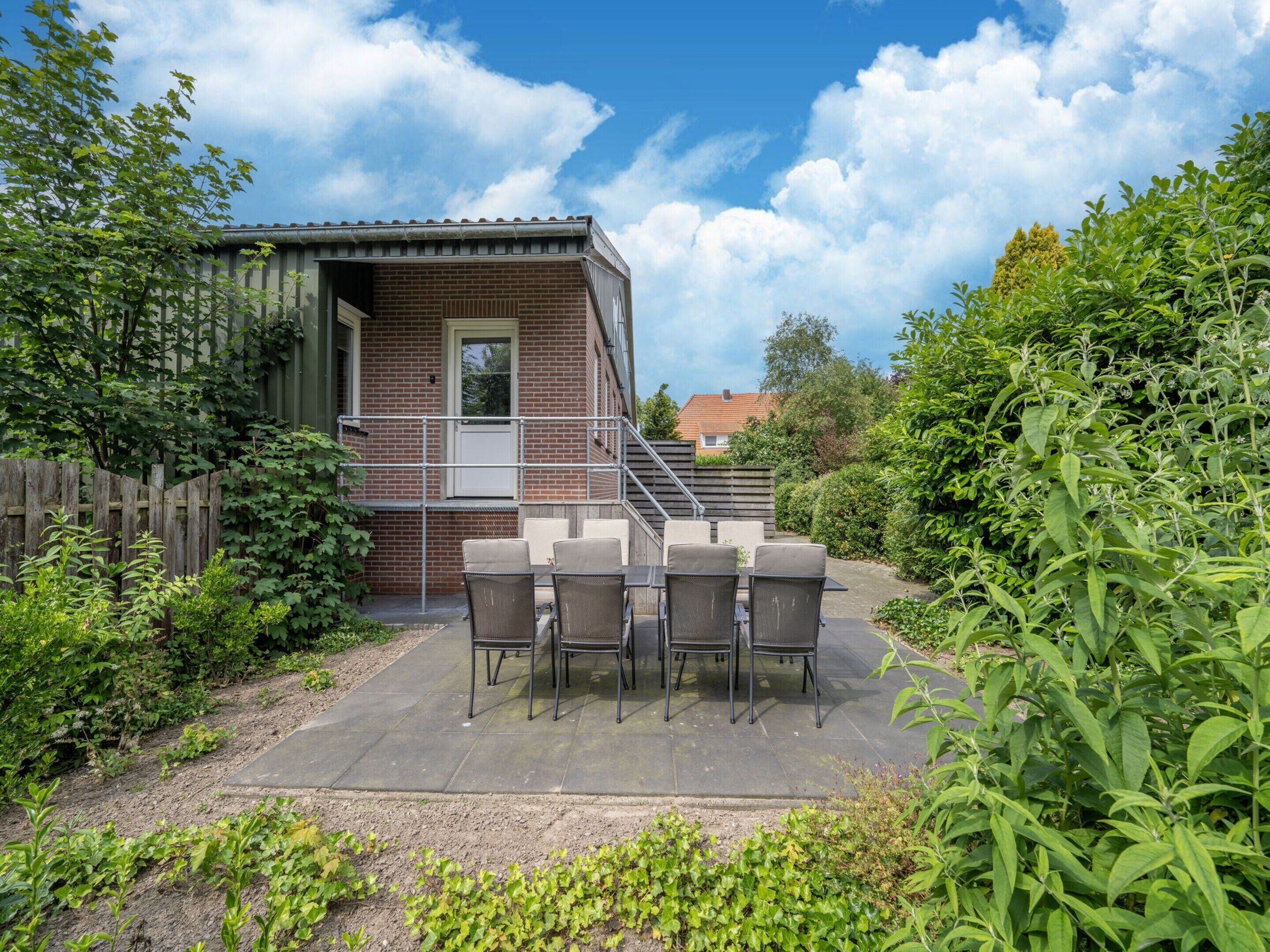 A patio with a brick building, outdoor furniture, and a wooden fence.