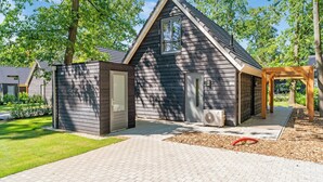 A modern house with a dark wooden exterior, a small porch, and a paved driveway. - Holiday Home in Lochem With Garden View (Lochem)