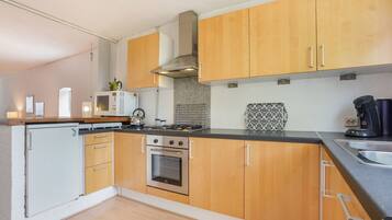 A compact kitchen with wooden cabinets, a built-in oven, a microwave, and a coffee maker.