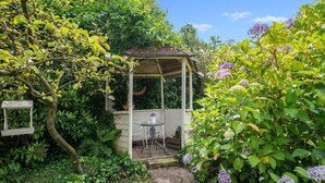 Un giardino con un gazebo, un tavolo e delle sedie.