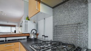 Una cucina moderna con piano cottura a gas, mobili in legno, un bollitore e una parete di impatto in granito.