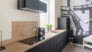 A modern kitchen with a wooden countertop, black cabinets, a stainless steel sink, and a black range hood. - Comfortable Holiday Home in Voorst With Garden (Voorst)