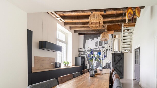 A modern kitchen with a wooden dining table, black cabinets, and a built-in stove. - Comfortable Holiday Home in Voorst With Garden (Voorst)