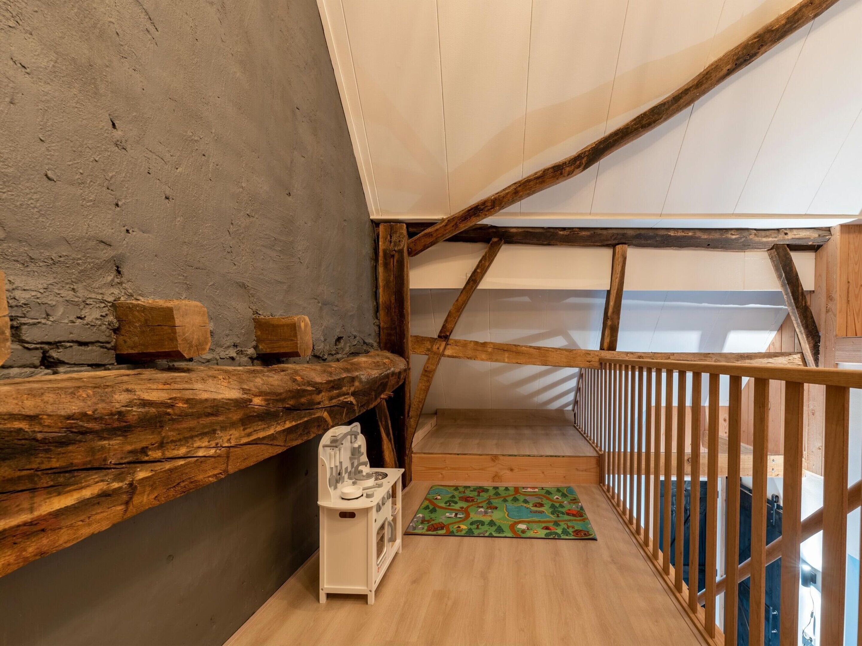A rustic attic room with exposed wooden beams, a sloped ceiling, and a small wooden shelf with blocks.