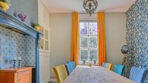 Un coin repas avec une table en bois, des chaises à l’assise rembourrée de tissu bleu et un sol à carreaux.