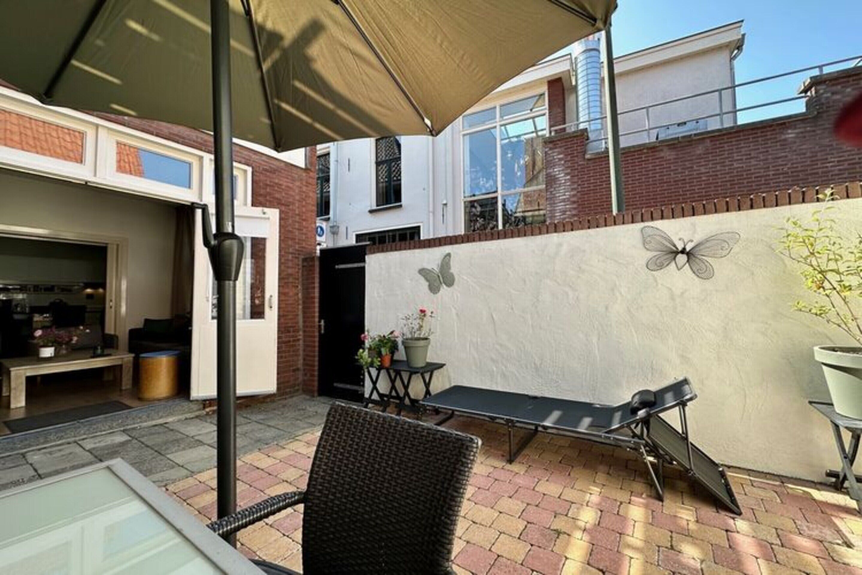 A patio area with a table, chairs, and a butterfly mural on the wall.