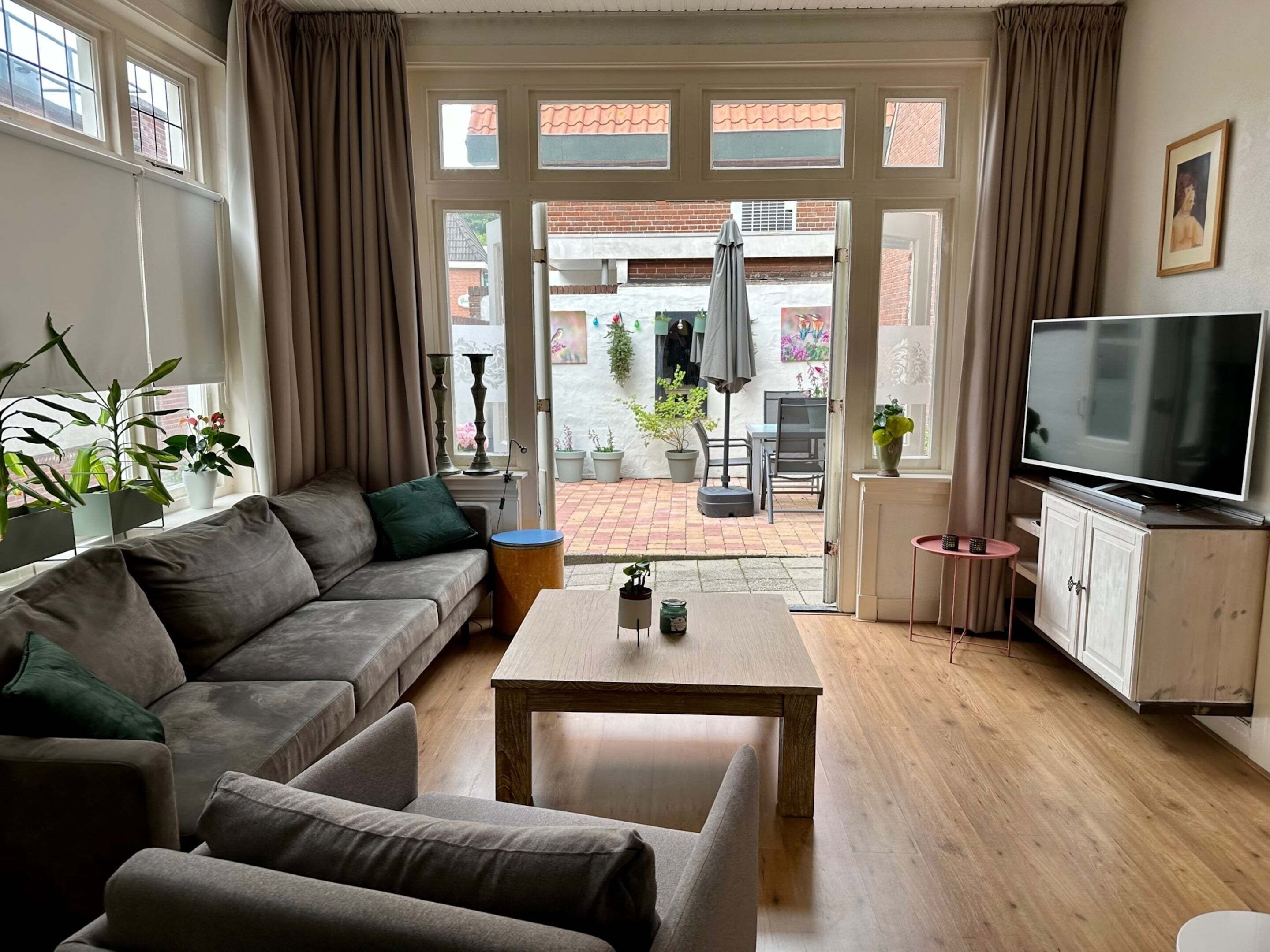 A living room with a sofa, a coffee table, a TV, and a view of the outside.