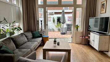 A living room with a sofa, a coffee table, a TV, and a view of the outside.