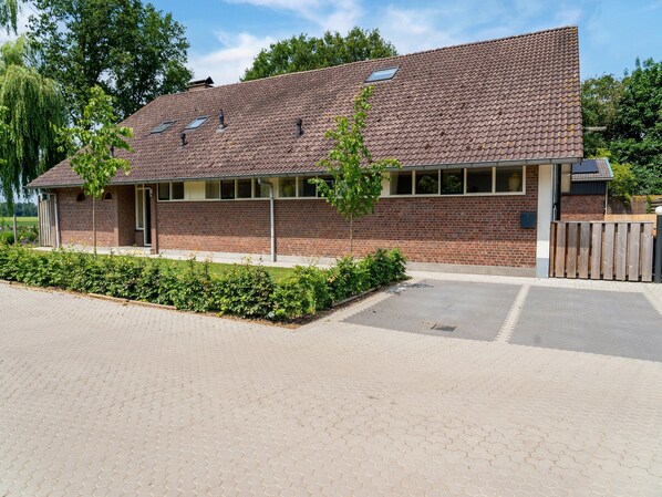 A brick building with a tiled roof, a small porch, and a paved driveway.