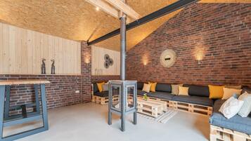 A cozy room with a brick wall, wooden ceiling, and a sofa with cushions.