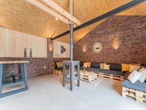 A cozy room with a brick wall, wooden ceiling, and a sofa with cushions.