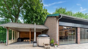 A covered outdoor area with a wooden bench, a hot tub, and a patio table. - Farmhouse in the Achterhoek With hot tub and Beach Volleyball (Megchelen)