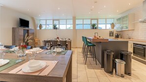 A modern kitchen with a dining area, large windows, and a TV mounted on the wall. - Farmhouse in the Achterhoek With hot tub and Beach Volleyball (Megchelen)