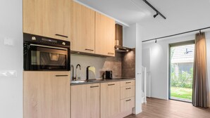 Ett modernt kök med träskåp, en inbyggd ugn och en kaffebryggare.