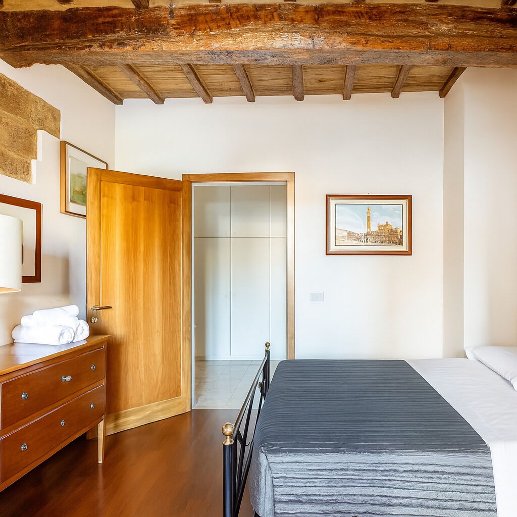 A bedroom with a wooden bed frame, a wooden dresser, and a door leading to another room.