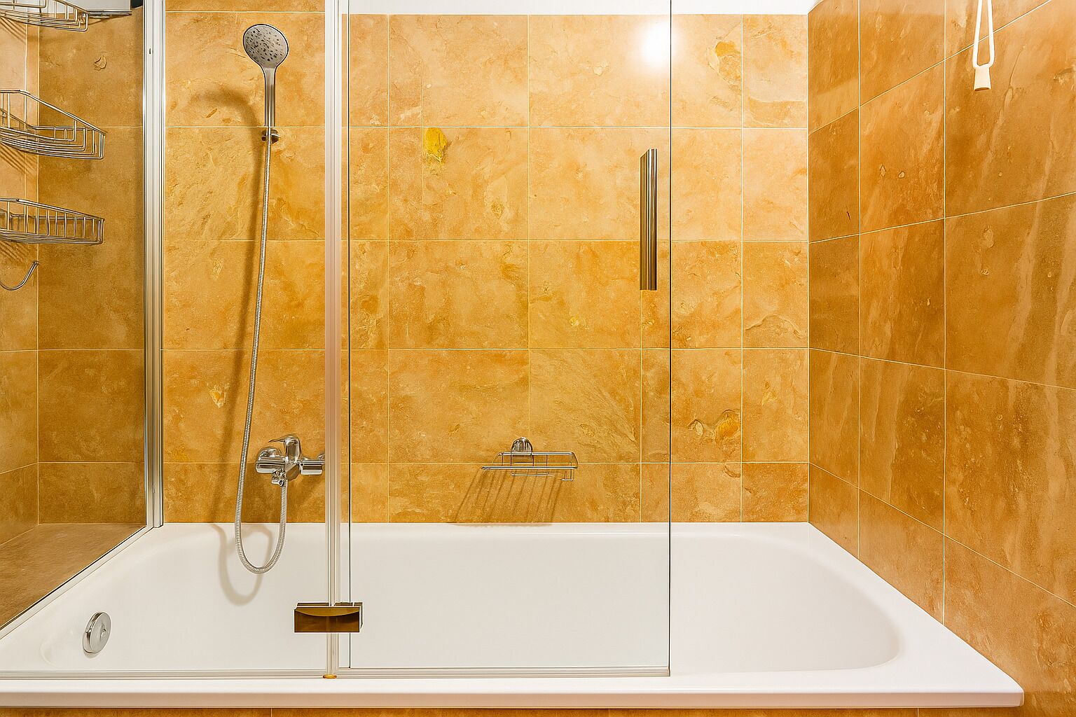 Et moderne badeværelse med en brusekabine med glasdøre, et hvidt badekar og en beige flisevæg.