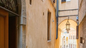A narrow cobblestone alleyway with a wooden door on the left and a stone wall on the right. - The Balcony Suite -Piazza del Campo View (Siena)
