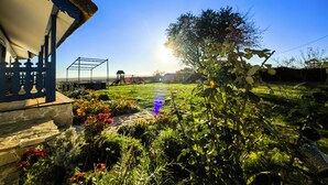 Un jardín con un pérgola, una pequeña estructura y un cielo despejado.