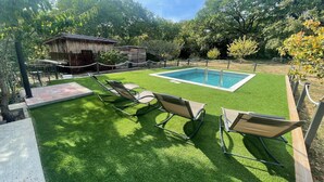 Un pati amb piscina, gespa artificial i gandules.