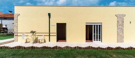 A yellow building with a patio, a door, and a window.