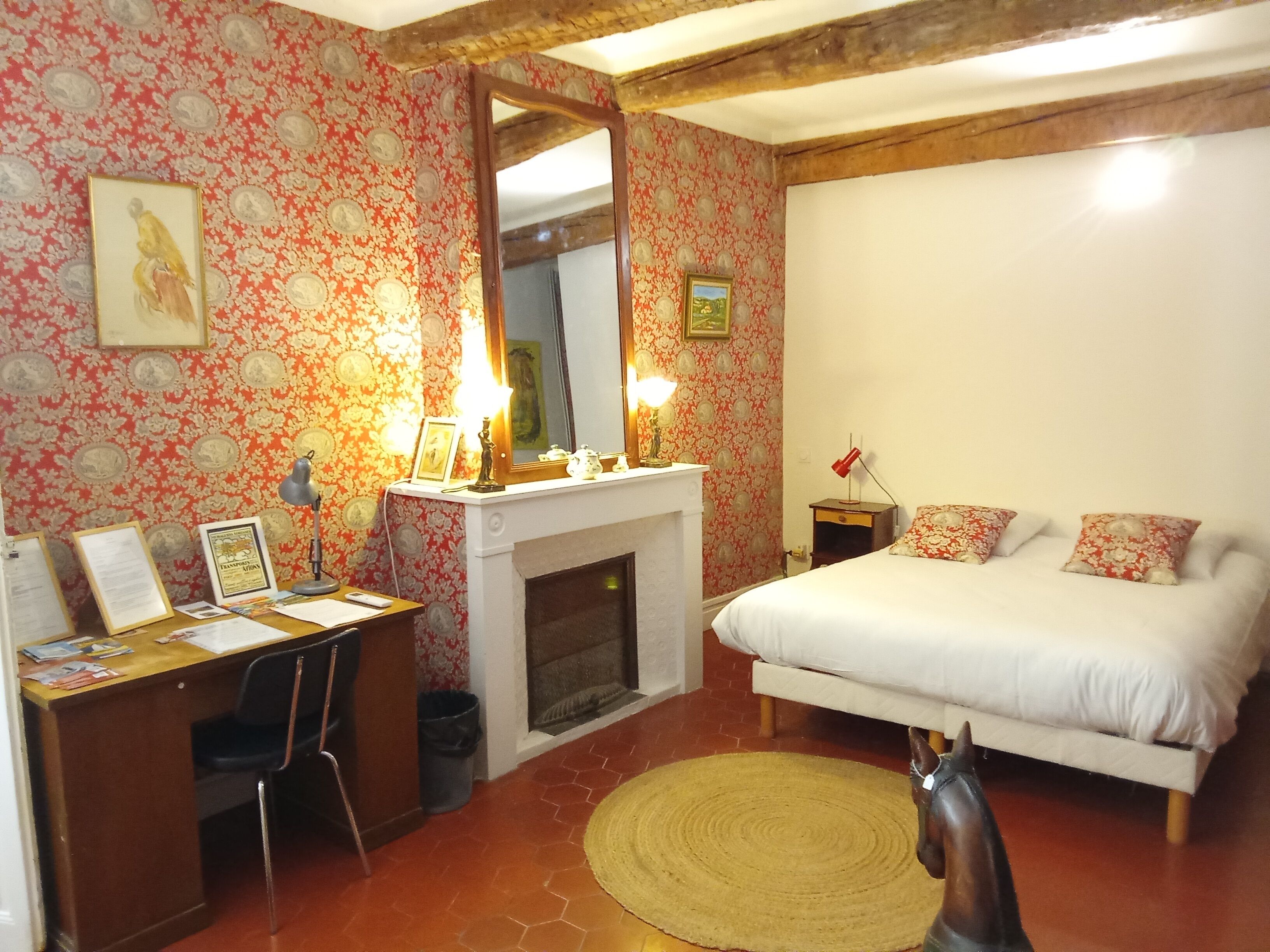 Un dormitorio con cama, escritorio, silla, chimenea y una estatua de un caballo.