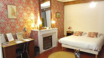 Un dormitorio con cama, escritorio, silla, chimenea y una estatua de un caballo.