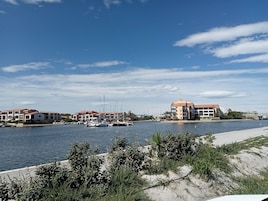 Un puerto deportivo con barcos, una playa arenosa y edificios con tejados rojos.