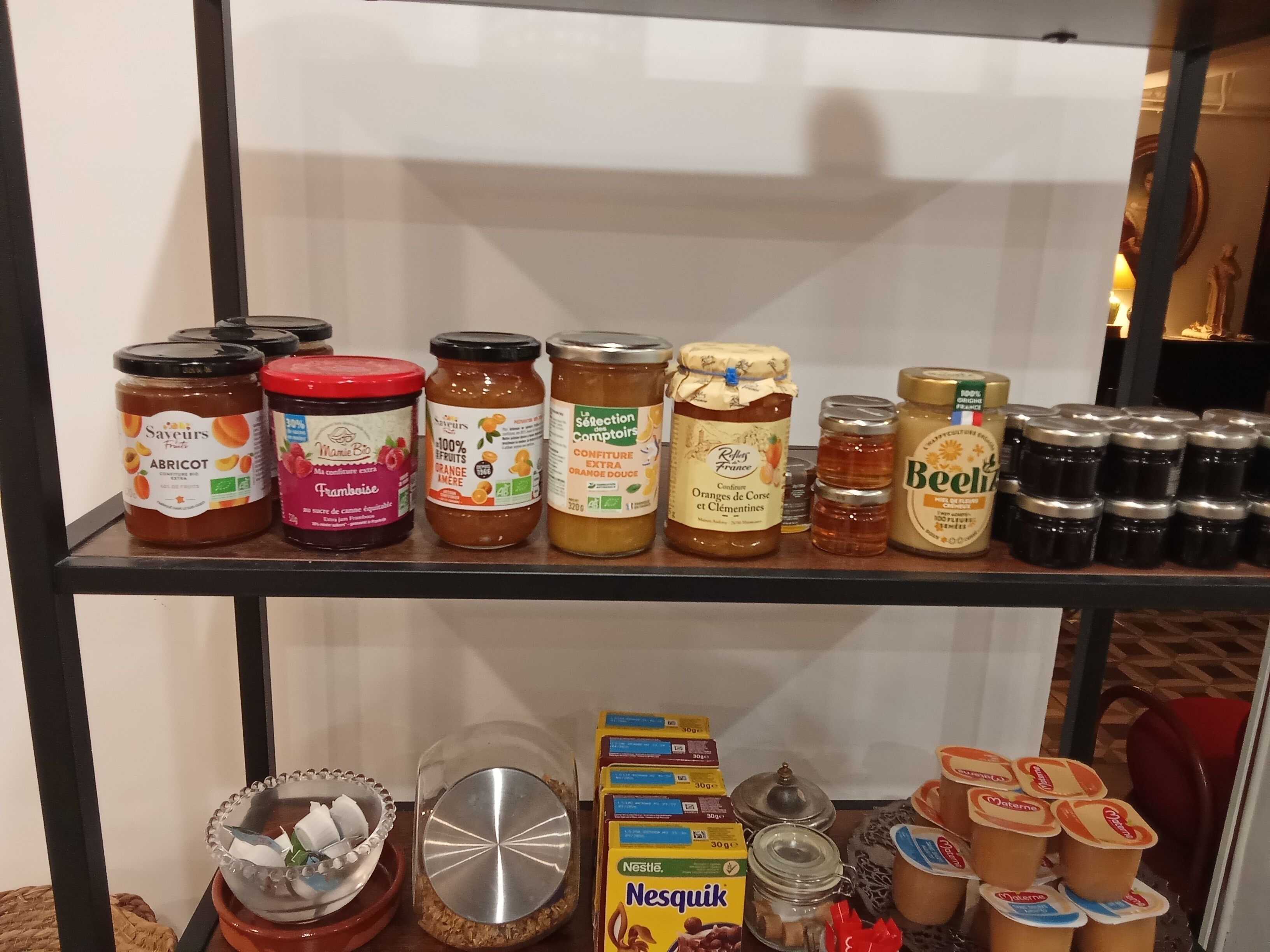 A shelf with various food items including jars of preserves, honey, and condiments.