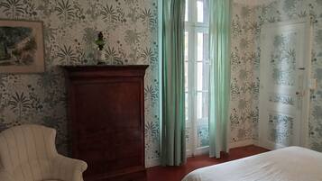 Una habitación con una cama, una silla, un armario de madera y una puerta.