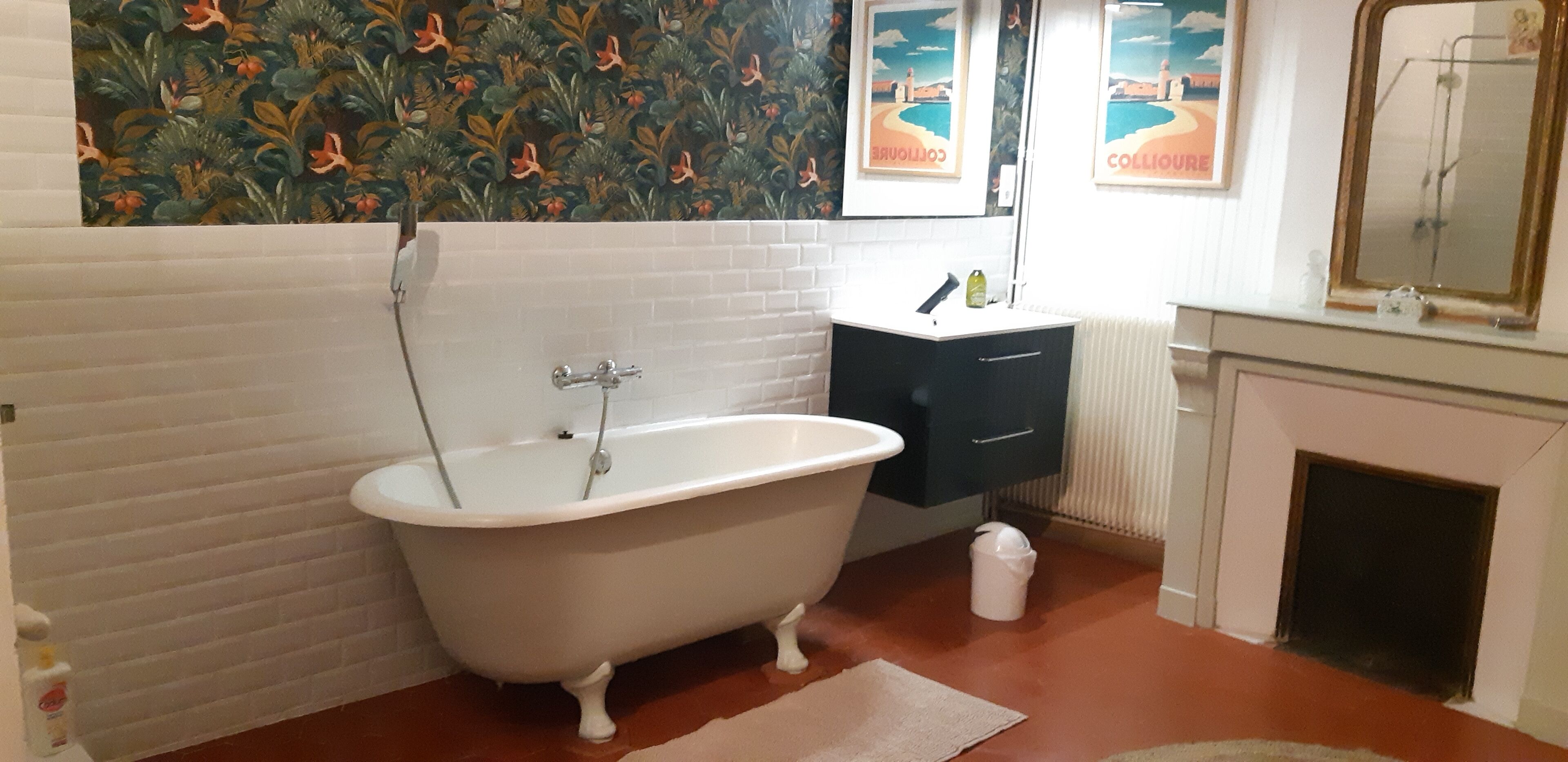 Un baño con una bañera tipo pata de león blanca, un lavabo blanco, un mueble oscuro y un espejo sobre el lavabo.