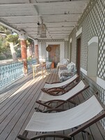 A wooden deck with lounge chairs, a table, and a door leading to an interior space.