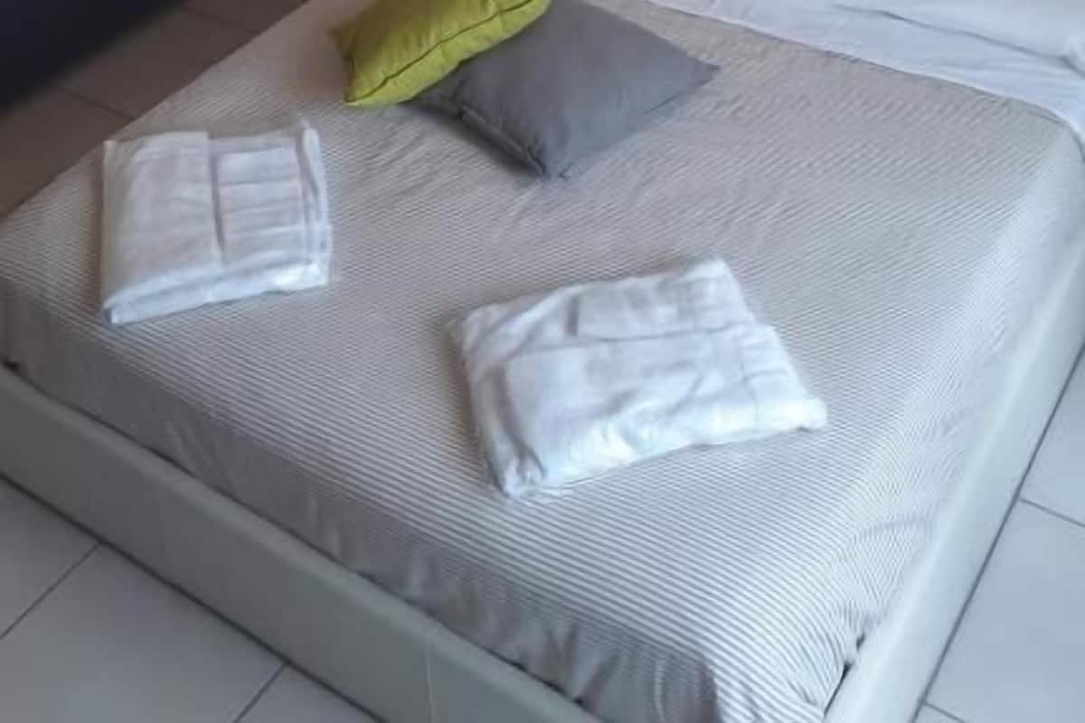 Una habitación de hotel ordenada con una cama, un sofá y una pequeña mesa.