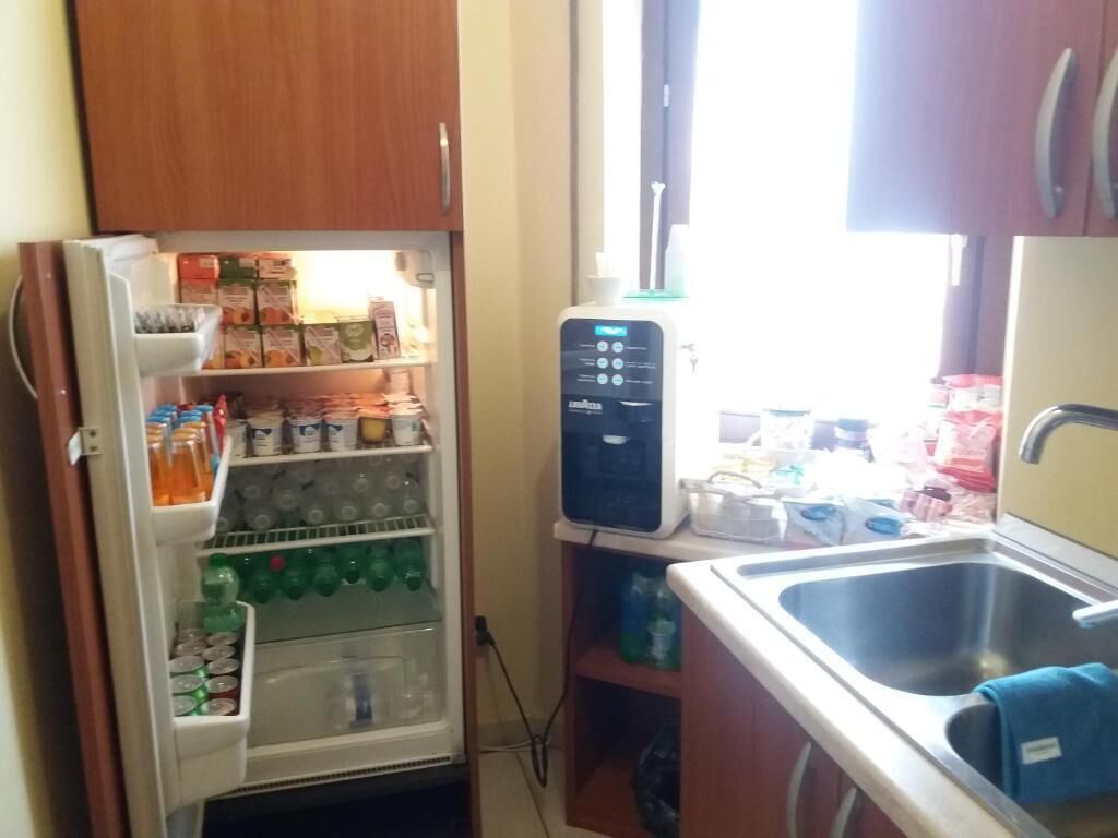 Eine kleine Küche mit Kühlschrank, Mikrowelle und Spüle.