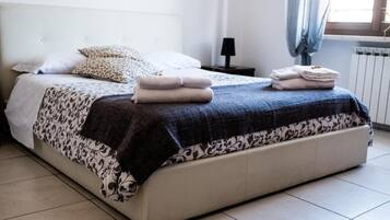 Ein ordentlich bezogenes Bett mit gemusterten Bettwäsche und gefalteten Handtüchern.