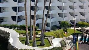 A modern building with multiple balconies and palm trees in front. - El Cardenal (Mogan)