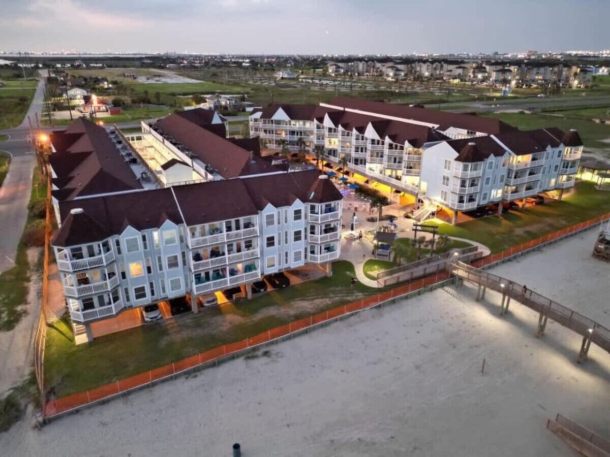 Een meerhoog hotel met een centrale binnenplaats, buiten zitplaatsen en een pad naar het strand.