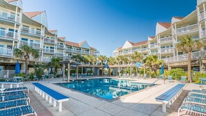A hotel with a swimming pool, multiple balconies, and outdoor seating areas. - Easy Beach Access! Charming Beachside Condo! (Galveston)