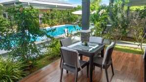 Une terrasse extérieure avec une piscine, des meubles en osier et un pilier en pierre.