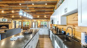 Une cuisine moderne avec un plafond en bois, un îlot central, des appareils en acier inoxydable et une vue sur l’extérieur.