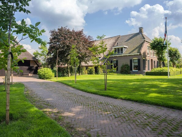 A brick house with a paved driveway and a well-maintained lawn.