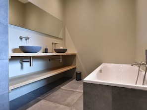 A modern bathroom with a large bathtub, two vessel sinks, and a mirror above the sink. - Dwingeloo Farmhouse Retreat (Dwingeloo)