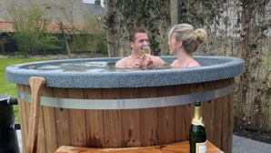 Ett bubbelbad med en träbänk och en flaska champagne.